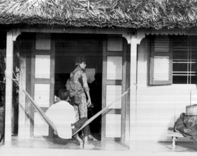 Photo:  POLICE FIELD FORCE: ENTERING HOUSE TO CONDUCT SEARCH. These men were trained to search for hidden documents, weapons, and other items which were stored in caches by the Viet Cong. Each member of the household was also searched.