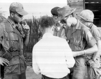 Photo:  VIETNAMESE POLICE OFFICER WITH U.S. OFFICER from the 2d Battalion, 3d Infantry, 199th Light Infantry Brigade, checking identification of a detainee.