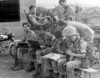 Photo:  POLICE FIELD FORCE REVIEWING PHOTOGRAPH ALBUM IN AN ATTEMPT TO IDENTIFY VIETCONG IN HAMLET. The album contains photos captured during U.S. Operation Cedar Falls, conducted in February 1967. 
