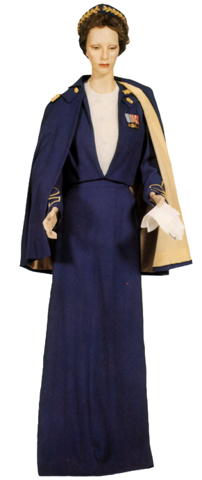 Plate 24. Officer's evening dress uniform (1952-1969), consisting of a blue wool jacket with gold bullion embroidered insignia of grade and branch on the sleeves, floor-length wool skirt, cape with gold rayon lining and gold bullion shoulder straps with embroidered insignia of grade, and a headband with laurel leaf, gold bullion embroidery. It was worn with a white silk shirtwaist, white kid gloves, and blue suede pumps. This uniform was not worn by enlisted women.