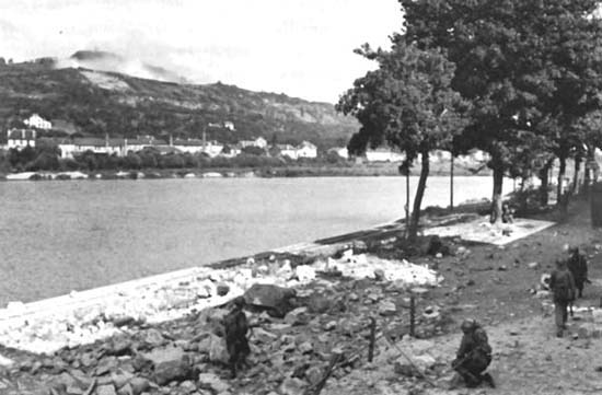 Photograph: Frontal Attack Across the Moselle. The 3d Battalion, 317th Infantry, prepares to take Mousson Hill, which may be seen across the river. 
