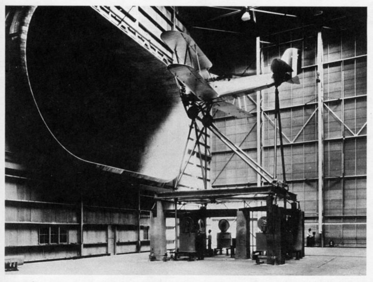 full size biplane is mounted infront of a wind tunnel for testing