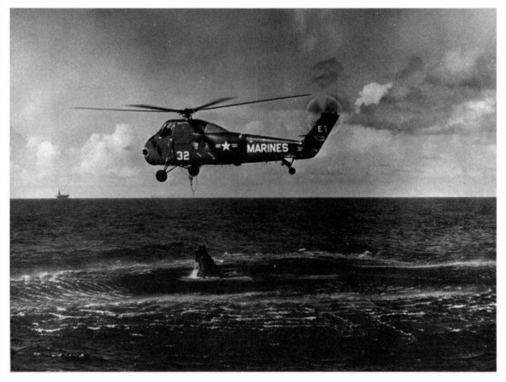 aerial photo of a rescue helicopter lifting a space capsule from the sea